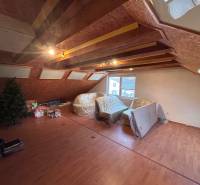 Tetőtéri szoba egy családi házban, fa dekorációjú padlóval és tetőablakokkal.