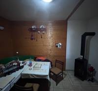 Családi ház fa burkolattal, cserépkályhával és étkezőasztallal.