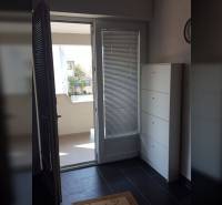 Erkély bejárata családi házban csempézett padlóval és fehér bútorokkal.