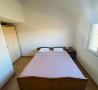 Hálószoba családi házban ággyal, éjjeliszekrénnyel és fa dekorációjú padlóval.