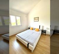 Hálószoba családi házban, fa dekor padlóval, ággyal és ablakkal.