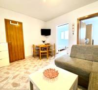 Nappali egy családi házban kanapéval, asztallal és falra szerelt televízióval.