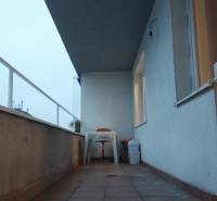 Erkély teraszburkolattal és műanyag bútorokkal egy egyszobás lakásban.