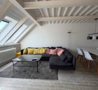 Nappali fa hatású padlóval, kanapéval és étkezőasztallal egy négy szobás lakásban.