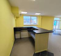 Világos üzlethelyiség pulttal és padlócsempével.