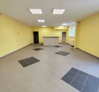 Kereskedelmi helyiségek belső tere csempével és recepcióval, mennyezeti lámpákkal megvilágítva.