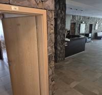 Kőfalak és faajtók vezetnek az egyszobás lakás irodájába.