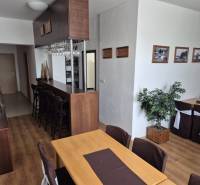 Egy étterem belső tere fa bútorokkal, kellemes világítással és dekoratív növényekkel.