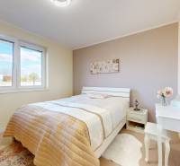 Hálószoba családi házban ággyal, fésülködőasztallal és finom színekkel.