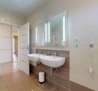 Fürdőszoba családi házban két mosdóval, zuhanyzóval és nagy tükörrel.