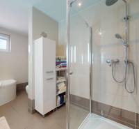 Fürdőszoba családi házban káddal, zuhanyzóval és tároló polcokkal.