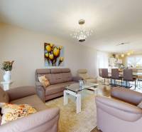 Családi ház nappalija bőrkanapékkal és üvegasztallal.