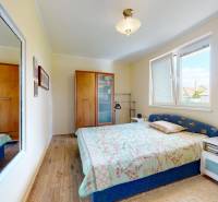 Hálószoba családi házban fa dekor padlóval, tükörrel és ággyal.