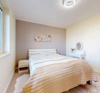 Világos hálószoba családi házban ággyal és asztallal.