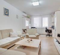 Nappali egy háromszobás lakásban, fa dekorációjú padlóval és kényelmes ülőgarnitúrával.