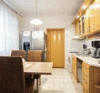 Konyha egy háromszobás lakásban étkezőasztallal, háztartási gépekkel és világos bútorokkal.