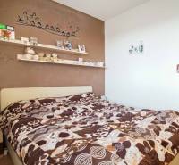 Hálószoba egy háromszobás lakásban, díszített fallal és feltűnő ágyneművel.