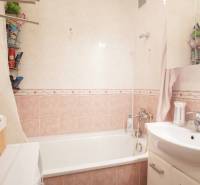 Fürdőszoba káddal és mosdóval egy háromszobás lakásban, csempék finom árnyalatokban.