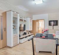 Nappali egy háromszobás lakásban, fa dekoros padlóval és sarokkanapéval.