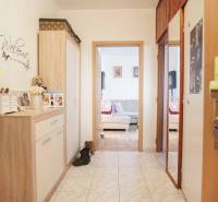 Folyosó egy 3 szobás lakásban csempével és hangulatos, fa dekorációjú bútorokkal.