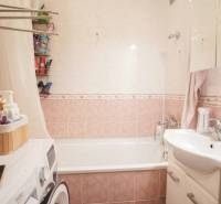 Fürdőszoba egy háromszobás lakásban káddal, mosdóval, mosógéppel és tárolóhelyekkel.