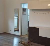 Nappali egy kétszobás lakásban, fa dekoros padlóval, fehér bútorokkal és tükörrel.