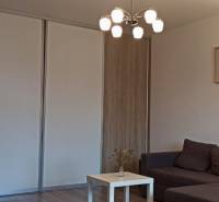 Nappali kanapéval, asztallal és fa dekorációjú padlóval egy kétszobás lakásban.