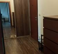 Folyosó egy kétszobás lakásban, fa dekoros padlóval, beépített szekrénnyel és tükrös elemmel.