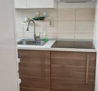 Konyha fehér szekrényekkel és rozsdamentes acél mosogatóval egy kétszobás lakásban.