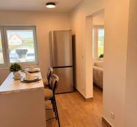 Konyha egy 2 szobás lakásban bárral, fa dekorációjú padlóval és hűtőszekrénnyel.