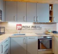 Konyha fa hatású padlóval, beépített készülékekkel és fali szekrényekkel egy kétszobás lakásban.