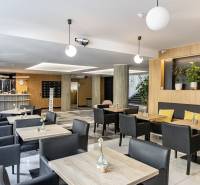 Irodák fa dekor padlóval, asztalokkal, fekete székekkel és növényekkel Pozsonyban.