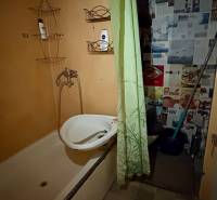 Fürdőszoba káddal és zöld függönnyel a garzonlakásban.