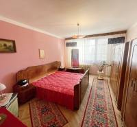 Hálószoba egy háromszobás lakásban piros kiegészítőkkel és fa dekorációjú padlóval.