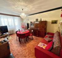 Nappali egy háromszobás lakásban szőnyegpadlóval és fa bútorokkal.