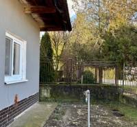 Családi ház Mýtné Ludanyban oldalsó kerttel és gyepfelülettel, kerítéssel körülvéve.