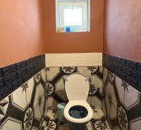 Fürdőszoba egy családi házban, hangsúlyos geometrikus csempével és narancssárga falakkal.