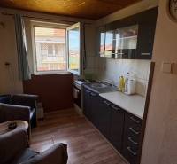 Konyha fa hatású padlóval és sötét szekrényekkel egy családi házban.