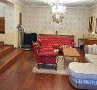 Nappali egy családi házban piros bútorokkal és televízióval, fa dekorációjú padlón.