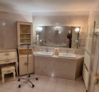 Fürdőszoba családi házban két mosdóval, tükörrel és díszes bútorokkal.