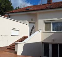 Családi ház Komáromban fehér homlokzattal és piros tetővel.