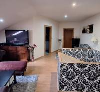 Nappali egy családi házban kanapéval, mintás tapétával és TV-vel.