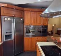 Konyha egy családi házban fa szekrényekkel és rozsdamentes acél készülékekkel.