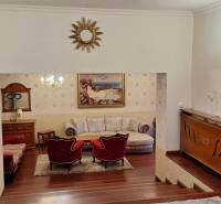 Luxusos családi ház belső tér fa dekorációval, kanapéval és műalkotásokkal a falakon.