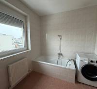 Fürdőszoba egy háromszobás lakásban káddal, mosógéppel és nagy ablakkal.