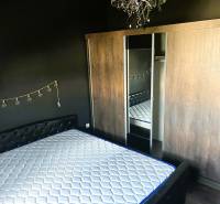 Hálószoba fekete falakkal, ággyal, tükörrel és szekrénnyel egy háromszobás lakásban.