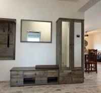 Folyosó egy háromszobás lakásban, fogassal és szekrénnyel, fa dekoros padlóval.