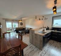 Nappali konyhával egy háromszobás lakásban, fa mintázatú padlóval.