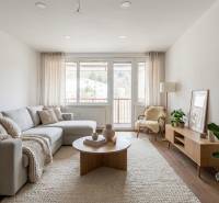 Nappali egy háromszobás lakásban, fa mintázatú padlóval, világos bútorokkal, növényekkel.