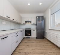 Konyha egy háromszobás lakásban fa dekor padlóval és felszereléssel.